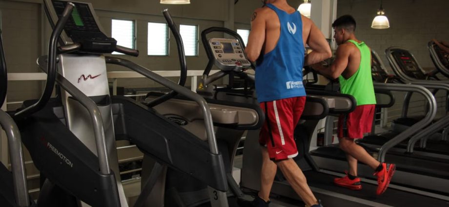 Two men running on treadmills in a modern gym, promoting fitness and health.